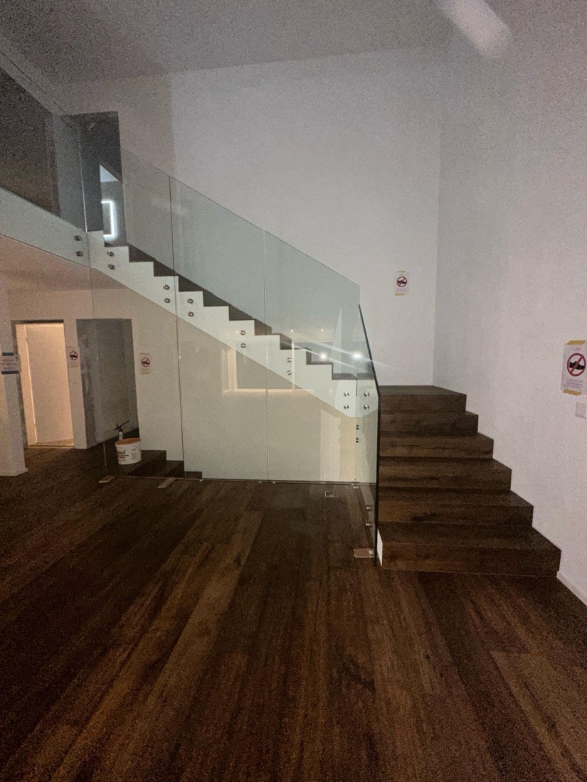 Dunkles Parkett am Boden und auf der Treppe mit Glasgeländer