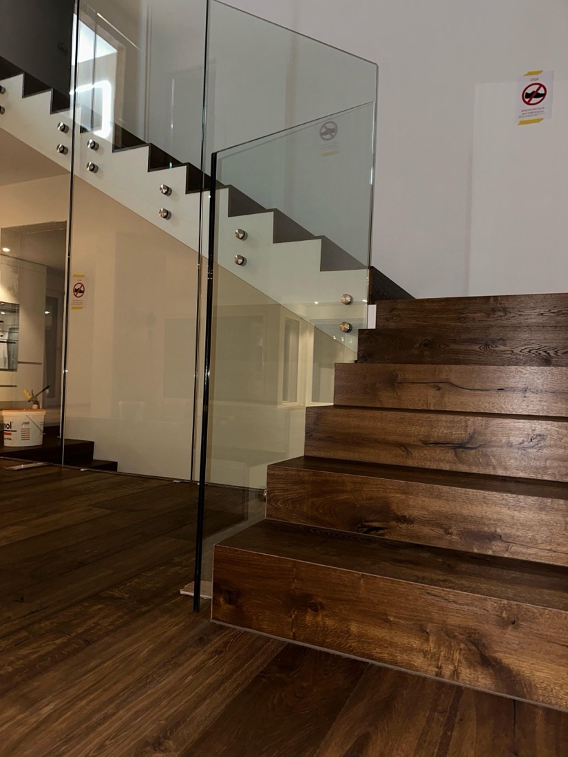 Dunkle Parketttreppe neben einer Glaswand