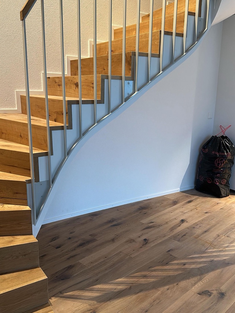 Geschwungene Treppe mit Parkett und Staketengeländer